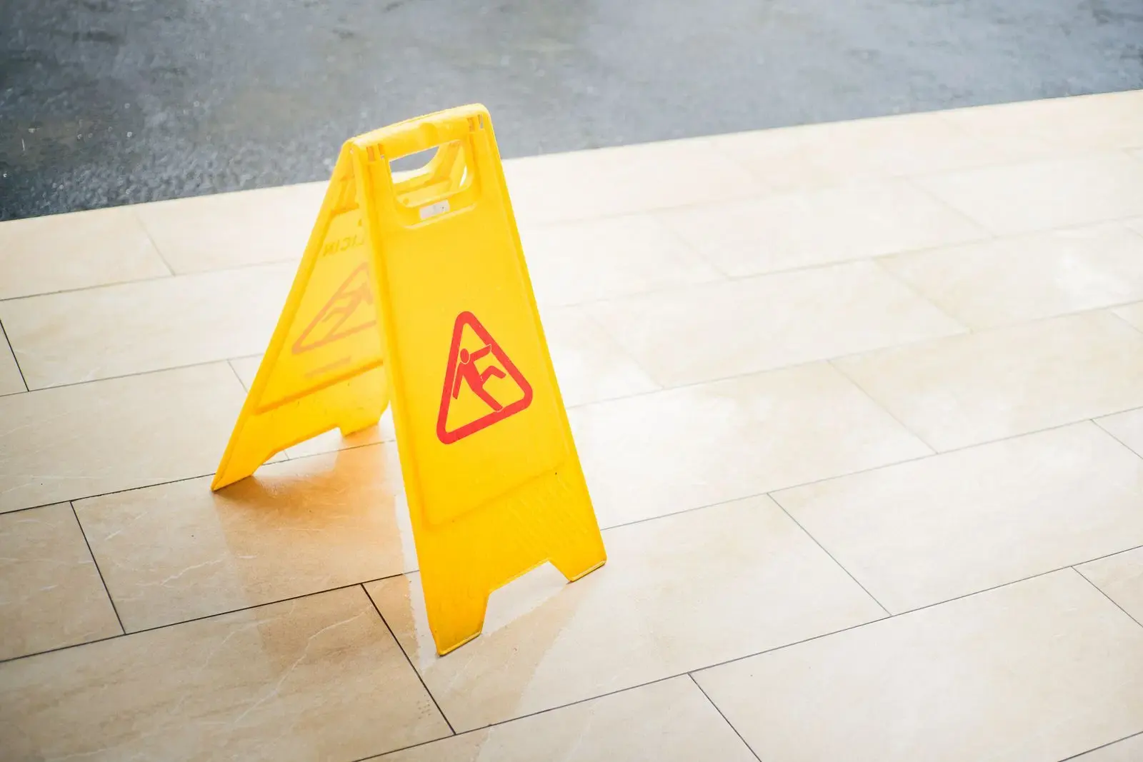 Yellow wet-floor caution sign on a water-covered tile floor